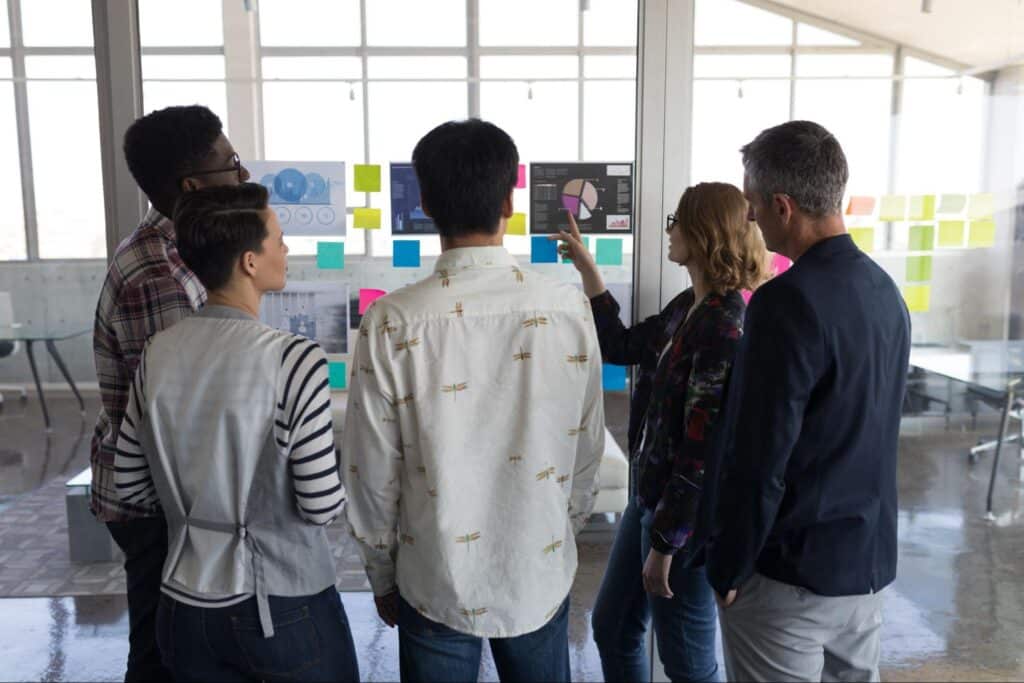 Team members collaborating in a modern creative workspace with visual aids.