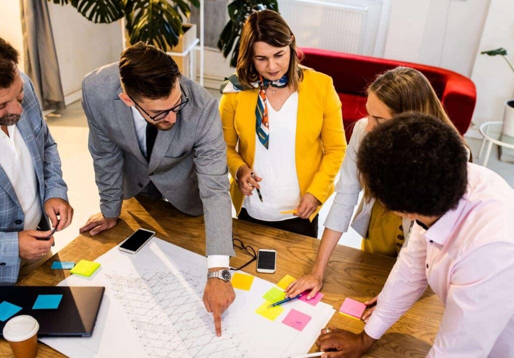 Team members brainstorming ideas collaboratively at a modern workspace with colorful notes.