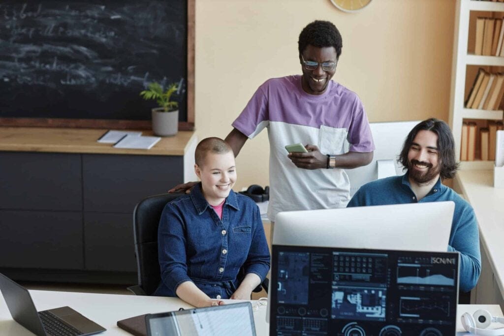 Cheerful IT managers analyzing scrum performance in a collaborative workspace.