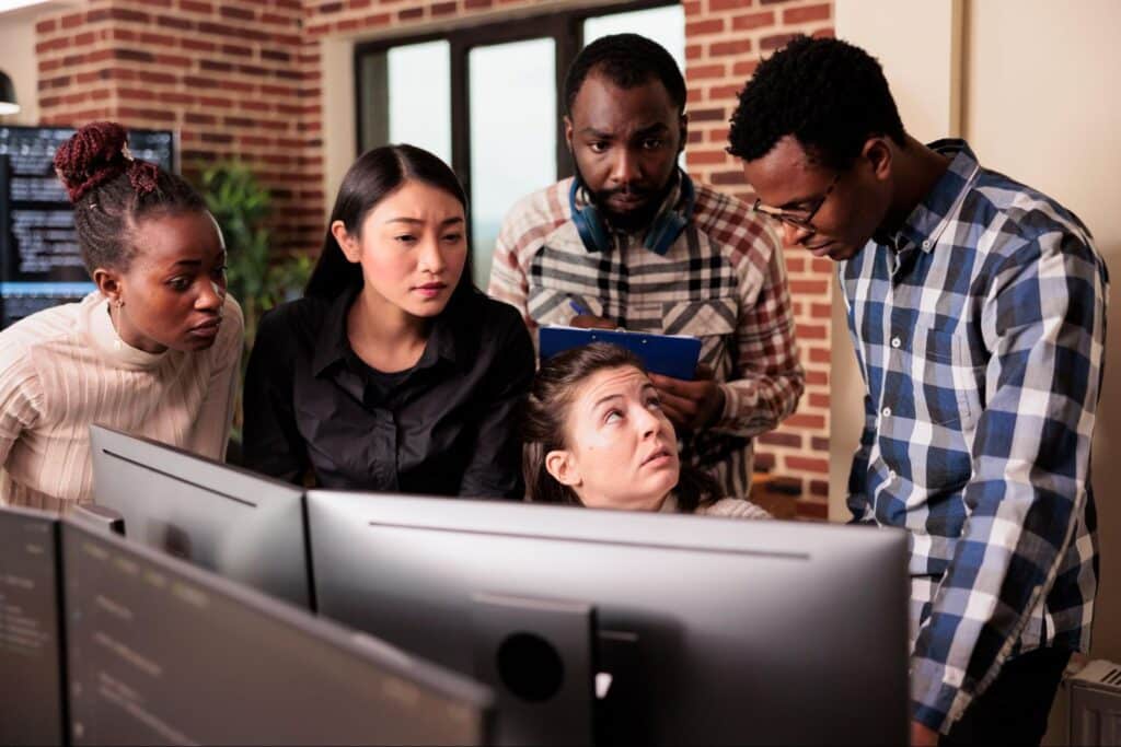 Diverse team collaborating and discussing projects in front of computer screens.