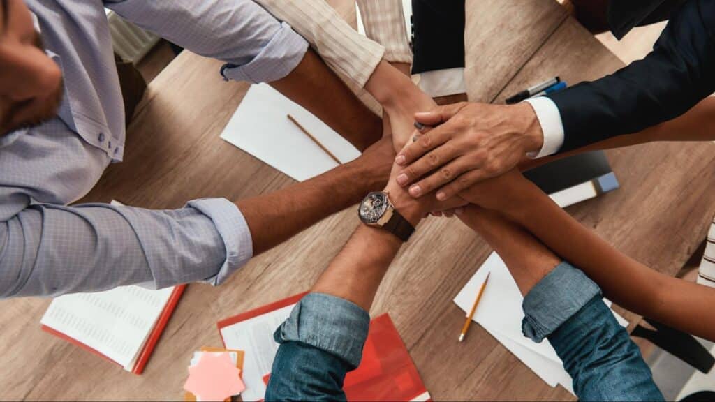 Team collaboration with hands joined on table, symbolizing organizational excellence