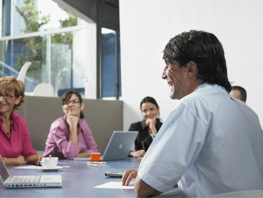 Team members engaged in Daily Scrum around a meeting table.