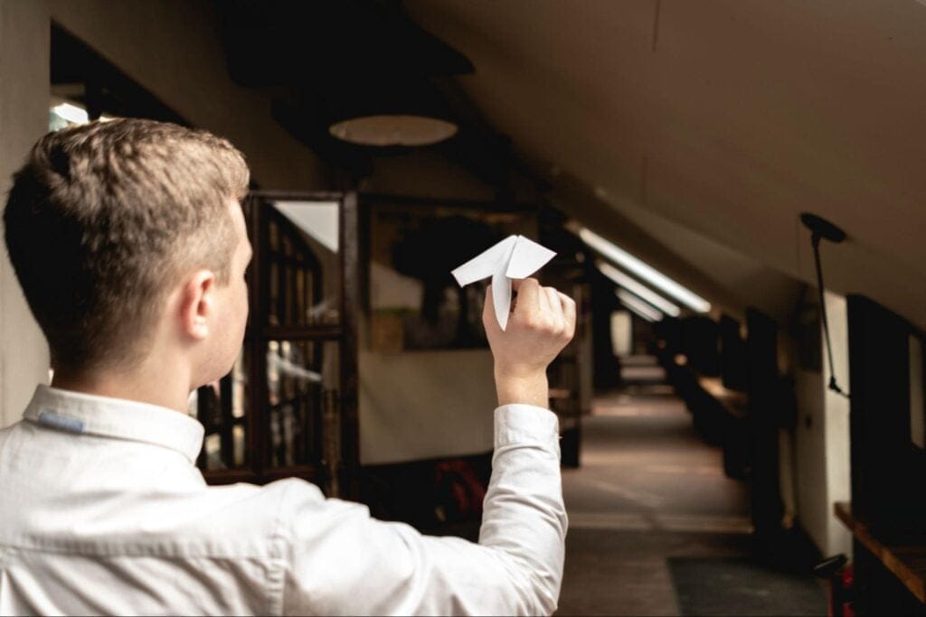 A young person launching a paper airplane in an office setting
