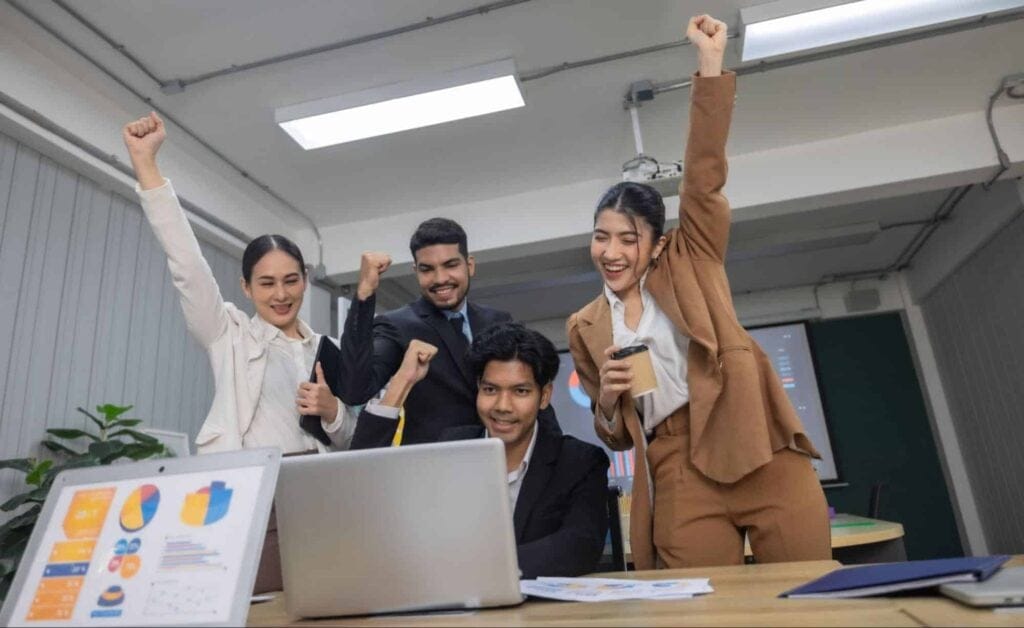 Team members celebrating success together at work with enthusiasm and joy.