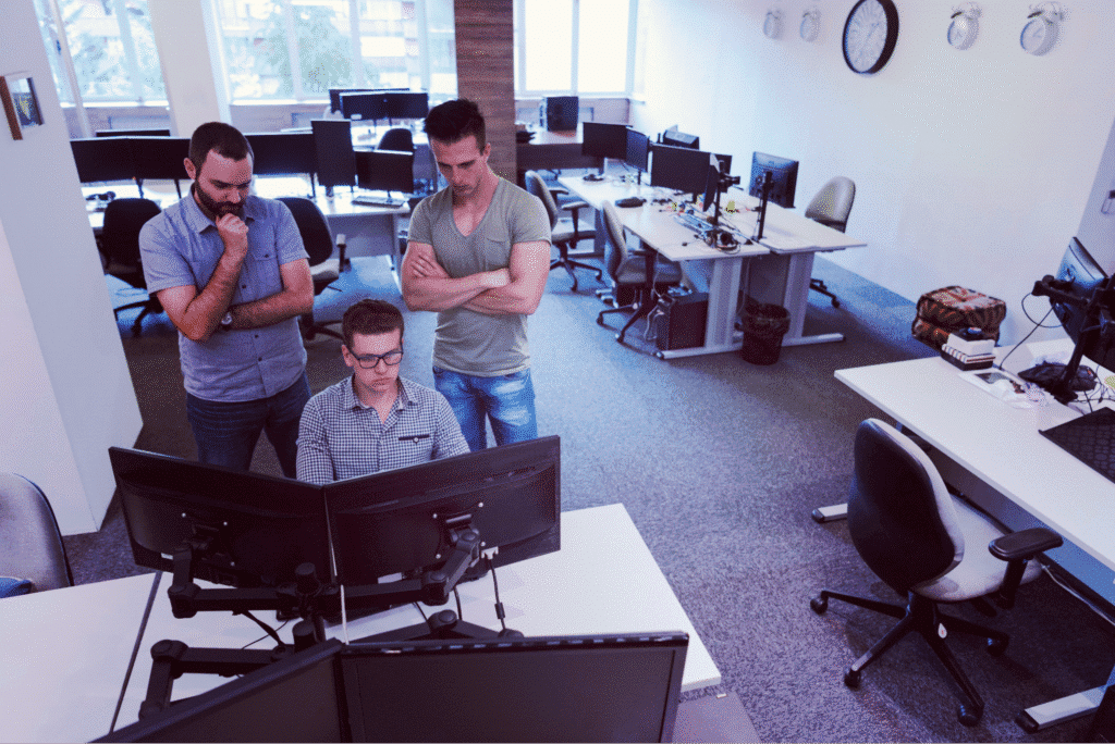 Software team members collaborating at computers in a modern office space.