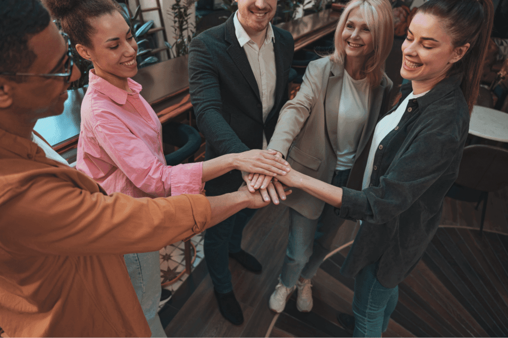 Team members joining hands, symbolizing unity, collaboration, and shared success.