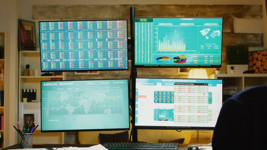 Home office with multiple monitors displaying stock market data and analytics.