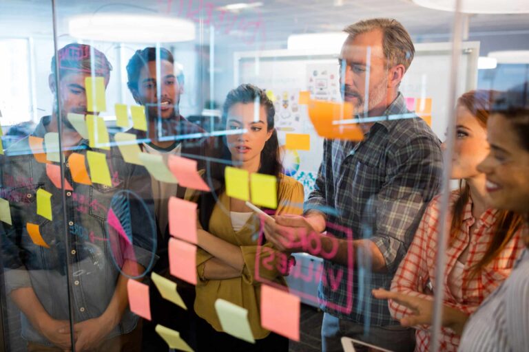 Team collaborating on sticky notes for agile transformation planning in a creative workspace.