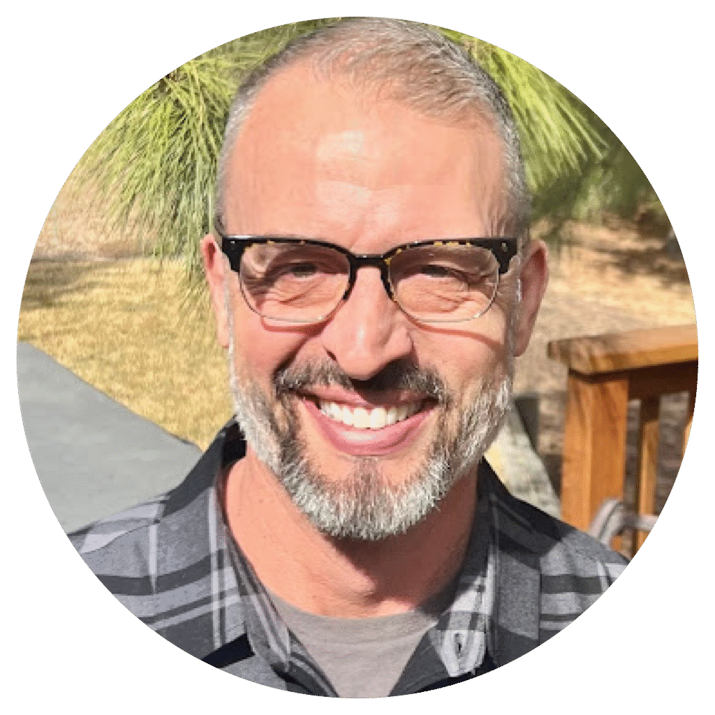 Smiling man in casual attire enjoying a sunny day outdoors.
