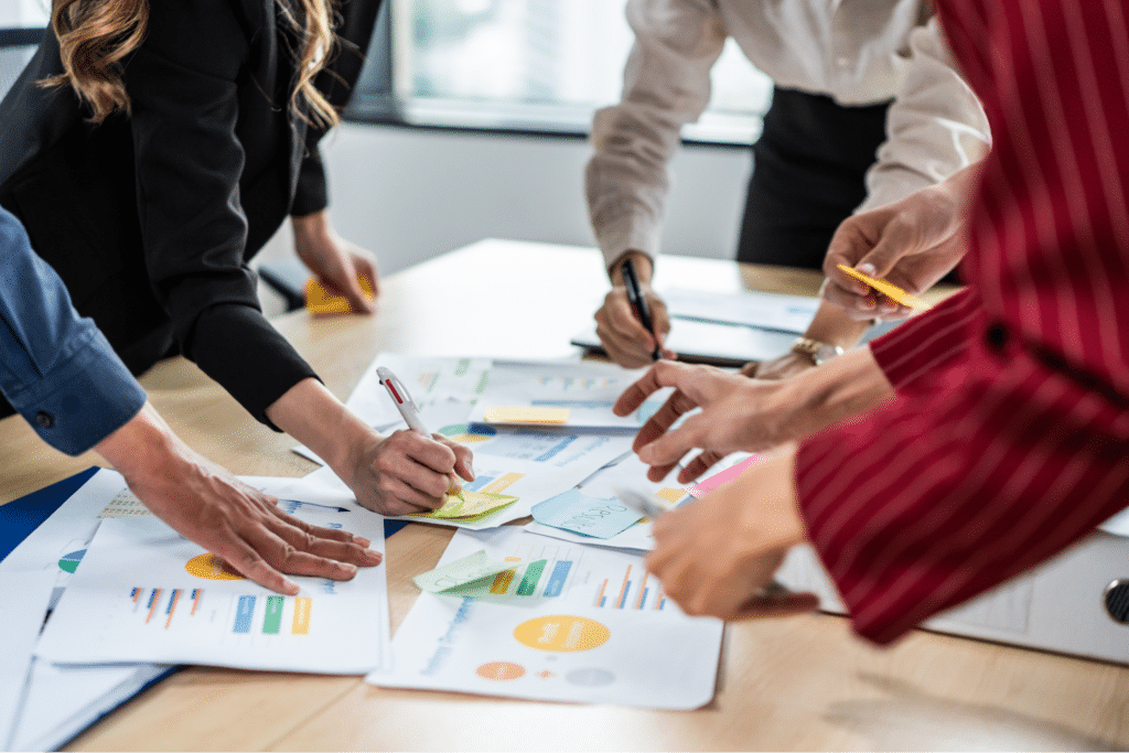 Team members collaborating on strategic planning with documents and notes in a meeting.