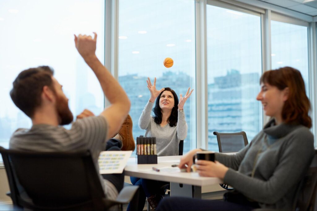 Team members enjoying playful collaboration in a bright office setting.