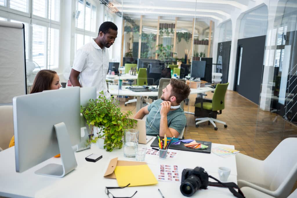 Graphic designers collaborating at a modern office workspace with creative tools.