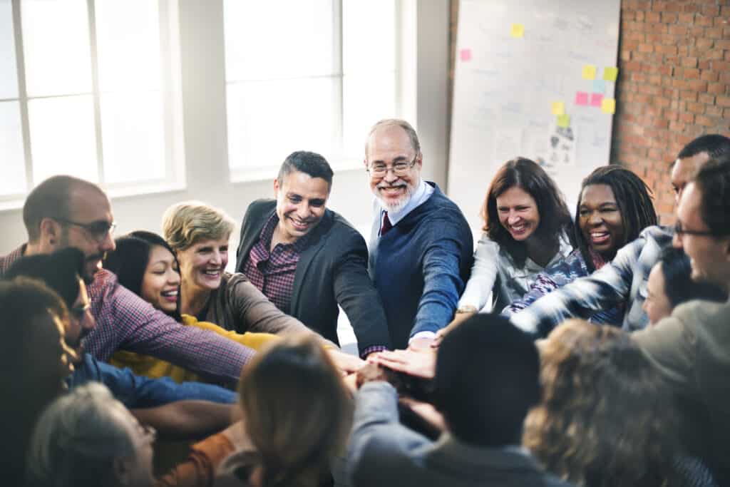 Teamwork and collaboration demonstrated through joined hands in a lively workshop.