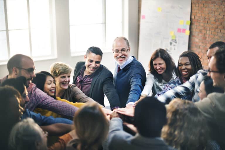 Teamwork and collaboration demonstrated through joined hands in a lively workshop.