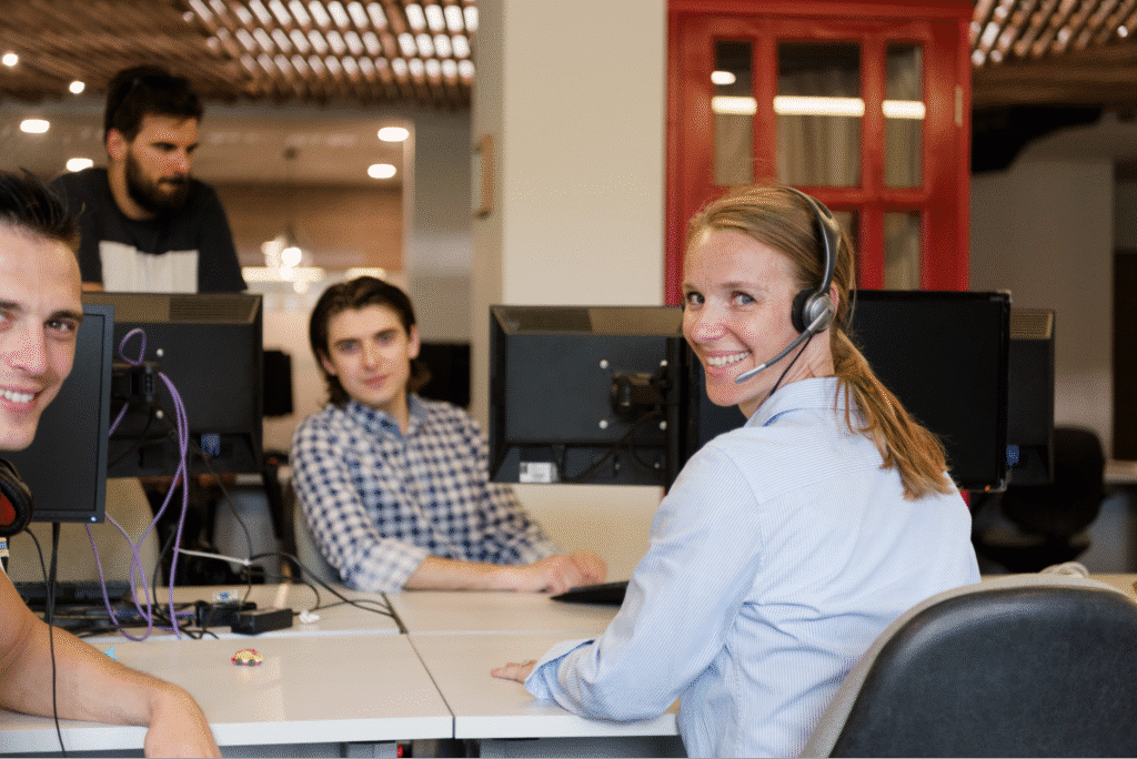 Agile customer support team collaboration in a lively office setting with headsets and computers.