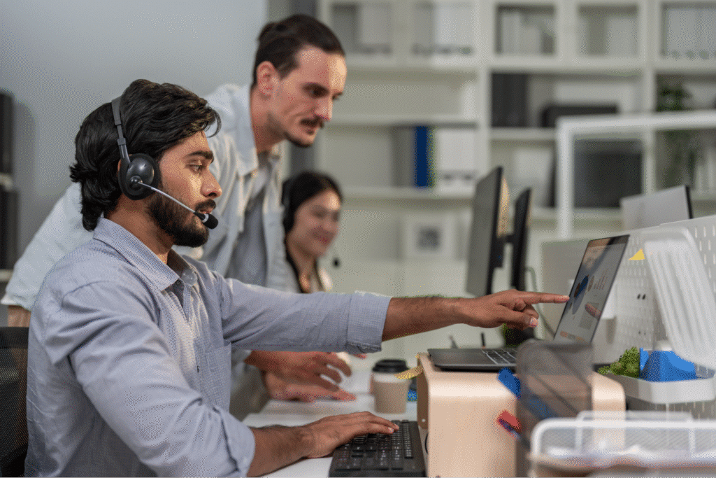 Colleagues collaborating in an office, using headsets and computers for effective communication.