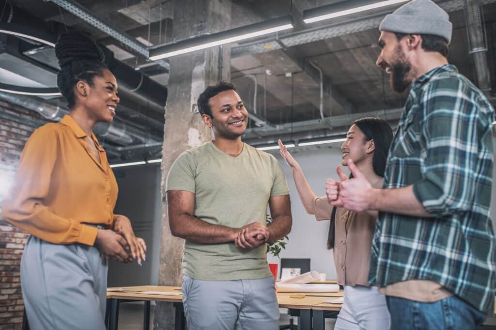 Interracial young happy colleagues communicating in office