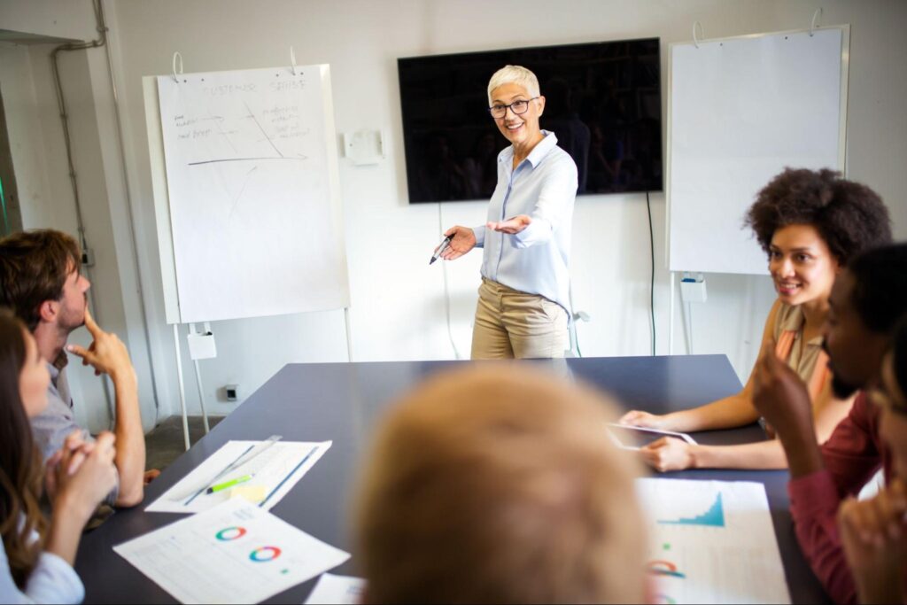 Business meeting featuring a speaker engaging with team members around a presentation table.