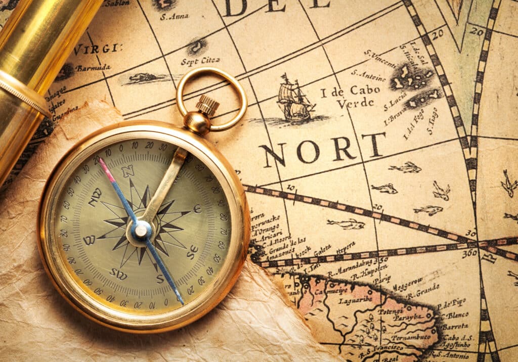 Antique compass and spyglass on a vintage map, showcasing navigation history.